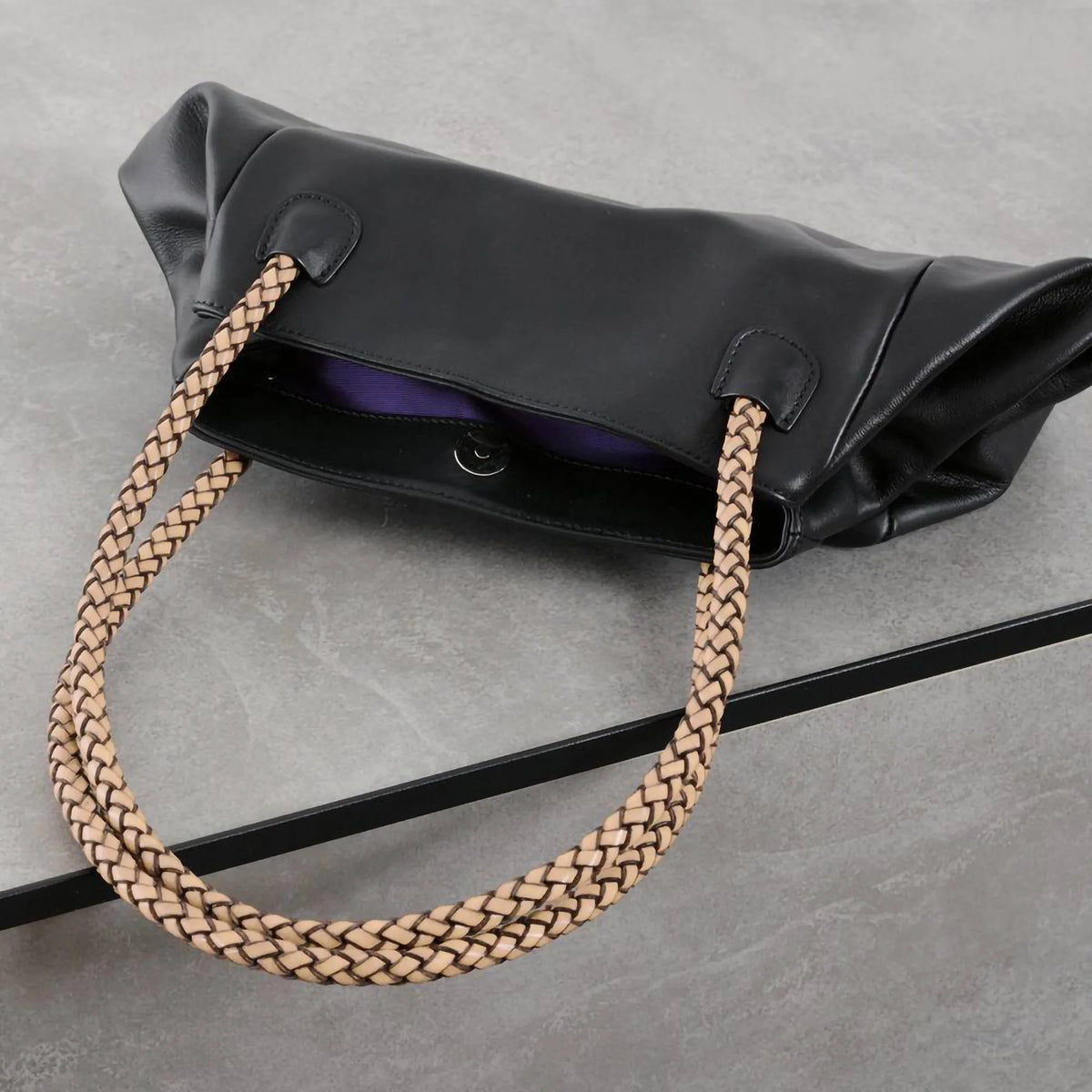 Ambientebild schwarzes Winkelprofil installiert am Boden auf dem eine Handtasche liegt