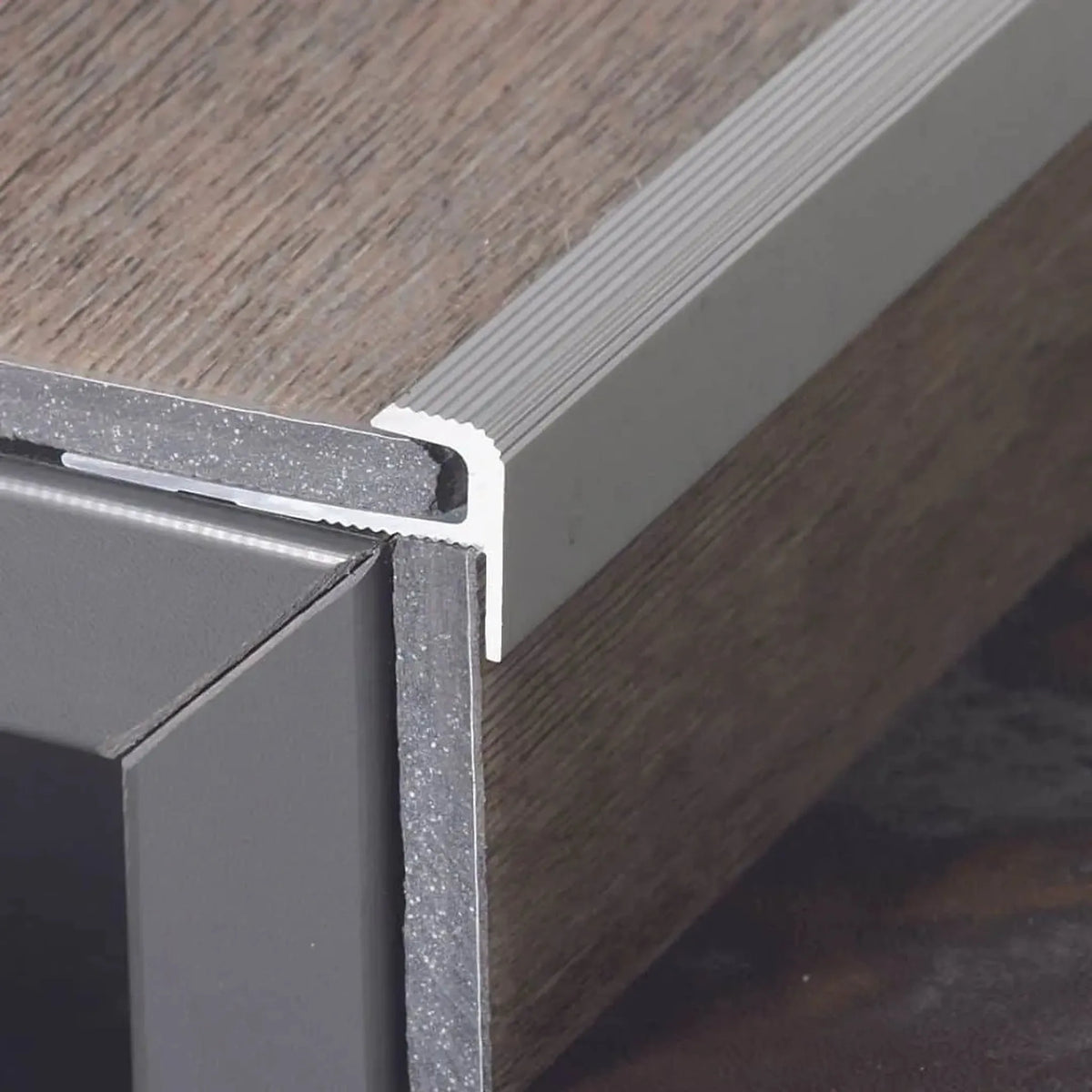profilé de nez de marche en forme de F en aluminium monté sur la marche, avec sol en vinyle inséré verticalement et horizontalement.