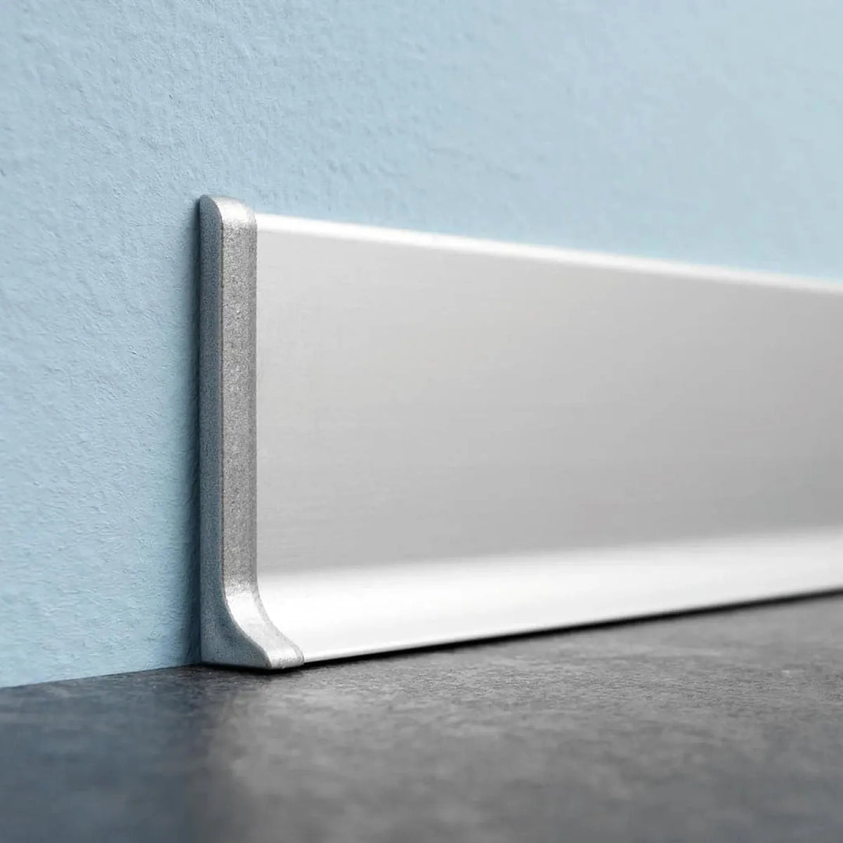 Skirting board mounted on a blue wall with left silver end cap skirting board aluminium