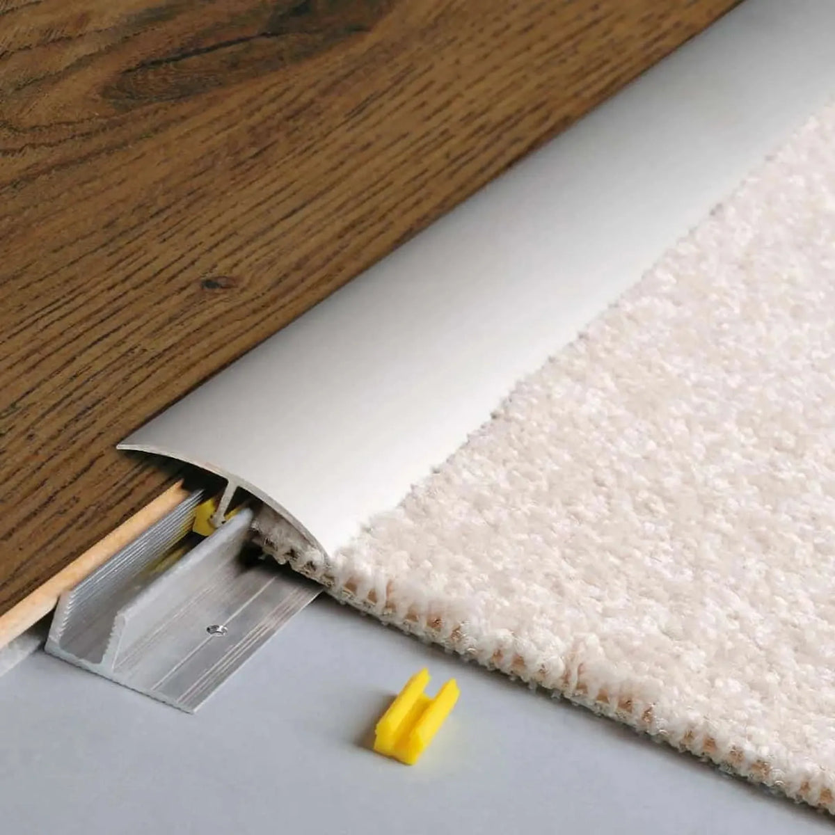 Ingebouwd zilver geanodiseerd hoogtecompensatieprofiel CLIP. Bruine, ingeschoven houten vloer aan de ene en lichte tapijtvloer aan de andere kant #A0003681
#A0003682