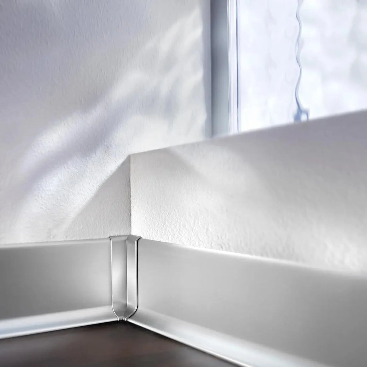 Plinthe posée au mur avec focus sur l'angle intérieur argent pour plinthe en aluminium #A0002042
#A0002047
#A0002052
#A0002057