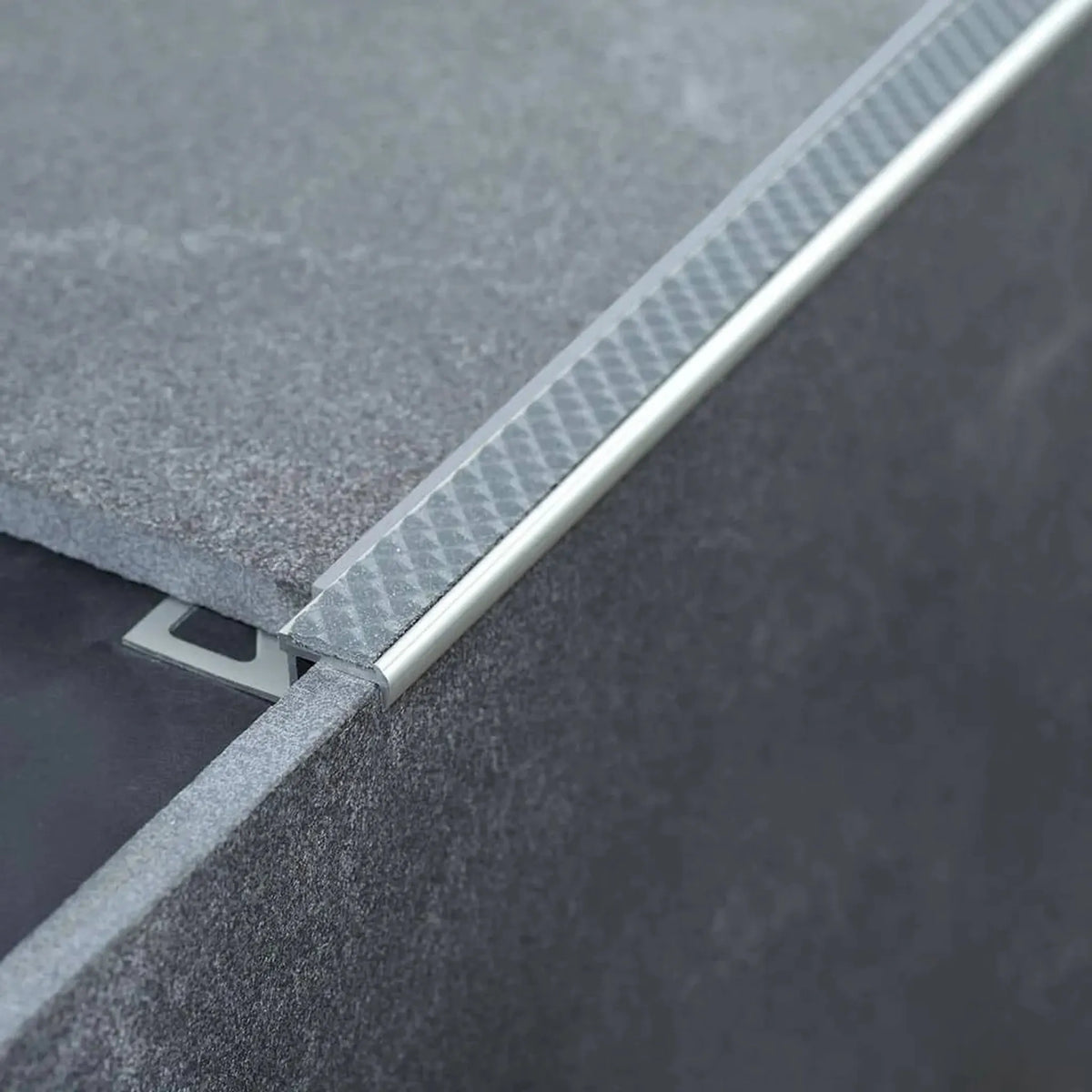 Profilé de nez de marche en aluminium antidérapant posé avec insert gris acier sur une marche carrelée grise #A0001725
#A0001736